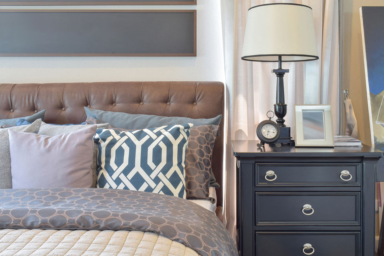 a bedroom with a bed and a nightstand with a lamp on it
